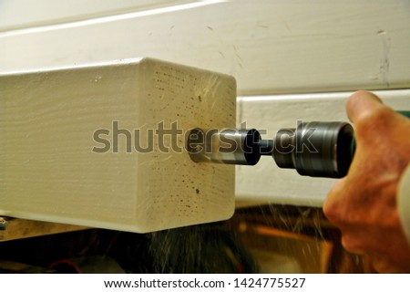 wooden beam girder element. Part of carport construction with a post. male Hand of carpenter is drilling a hole with an electric drill mashine in wooden beam. Elements of timber construction. 