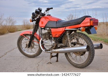 Red motorcycle stands on the empty road, vintage bike Royalty-Free Stock Photo #1424777627