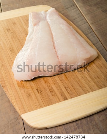Fresh halibut steaks on a wooden cutting board ready to cook