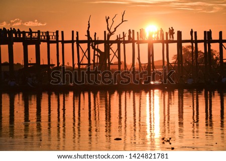 ubein bridge in myanmar which is built of ancient wooden logs during sunset when silhouettes of people are seen
