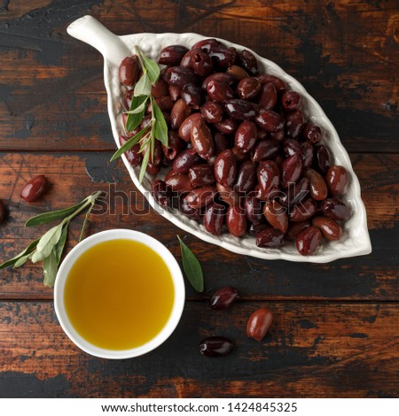 Extra virgin olive oil and kalamata olives on rustic wooden background