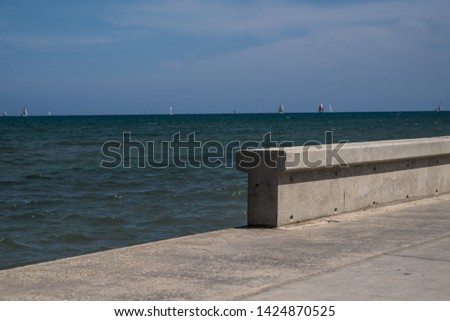 Cement wall separating the road from the beach. Protects pedestrians from the sea and is entrance to the beach