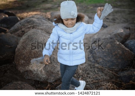 Portrait of a child, a little girl who walks on stones in the shore.
