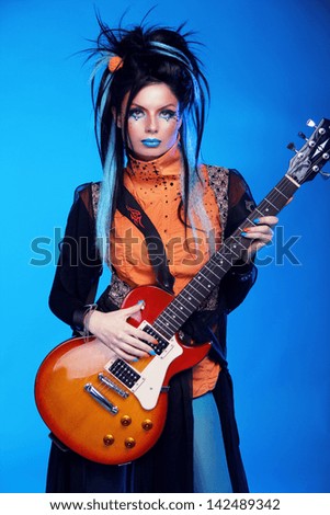 Rock girl posing with electric guitar playing hard-rock isolated on blue background