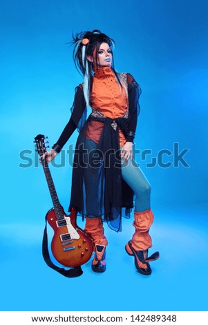 Rock girl posing with electric guitar isolated on blue background