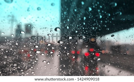 Car windshield with raindrop,blurred lighting of traffic in the city on rainy day at evening,colorful bokeh.