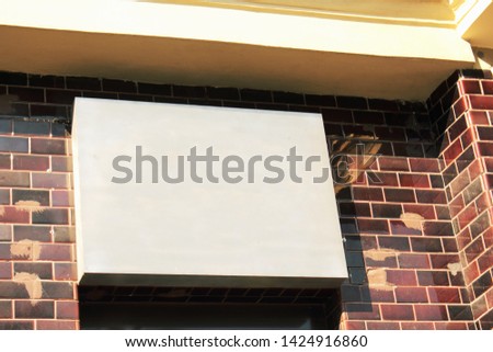 Blank business sign on black and red brick wall in sunshine