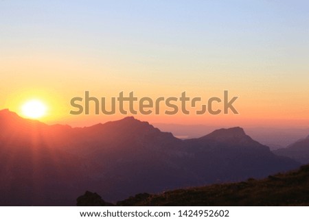 Colorful sunset in the swiss mountains with a raising sun behind the mountains