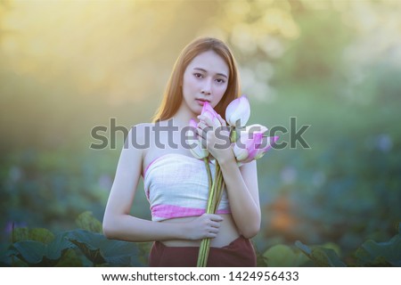 Picture of beautiful woman with lotus flower, Young beautiful woman relaxing with lotus flower, The girl holds the lotus flower in the field.