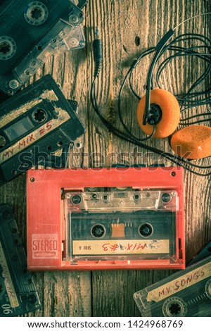 Vintage audio cassette, headphones and walkman on wooden table Royalty-Free Stock Photo #1424968769