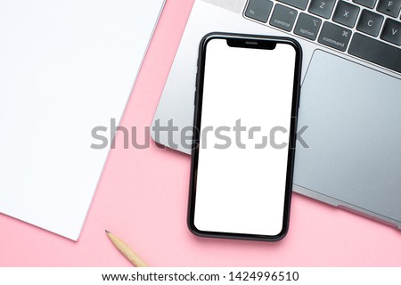 Mobile phone blank screen , laptop and business notebook on pink background with copy space for your text.Woman working desk.