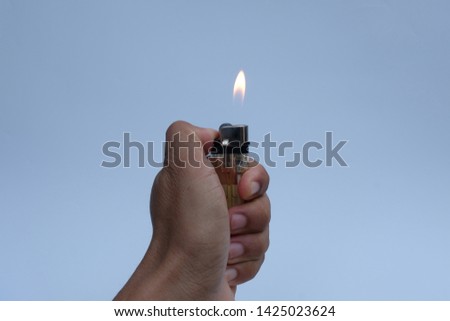Hand burning a lighter on white background.
