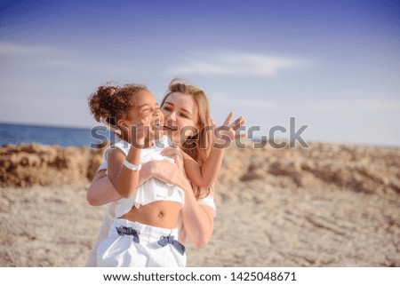 portrait of happy mother and daughter spending time together on the beach on summer vacation. Happy family traveling, cozy mood. Child kissing mother. 