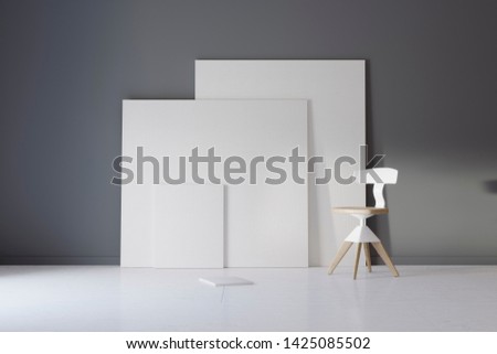 Pictures and chair in gray studio with atmospheric lighting