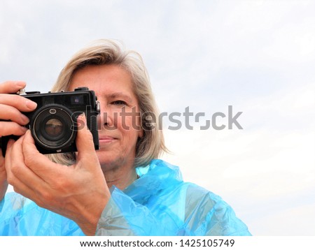 middle aged female photographer taking photos outdoors.
senior female amateur photographer taking photos. 