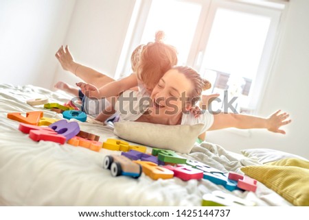Mother having fun with kids while playing with them in bedroom