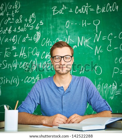 Portrait of handsome student looking at camera on background of chalkboard
