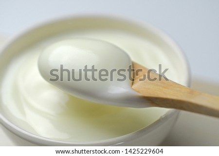 Bowl of sour cream yogurt with wooden spoon - close-up