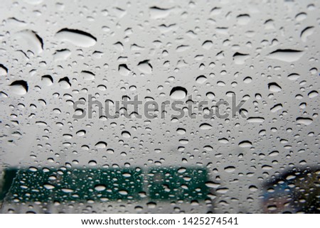 Close up Raindrops on the glass of window on the background of cloudy sky and guide post  in the rainy season. Raindrop wallpaper.