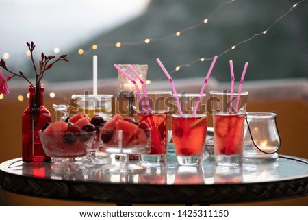 Bright summer hot still life at a small party. Drinks and dessert from fruits in red tones
