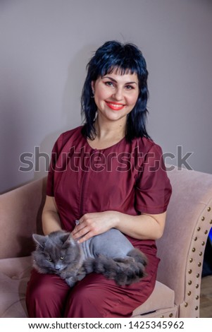 A woman in a medical suit with a cat. Woman doctor with a cat. Gray cat.