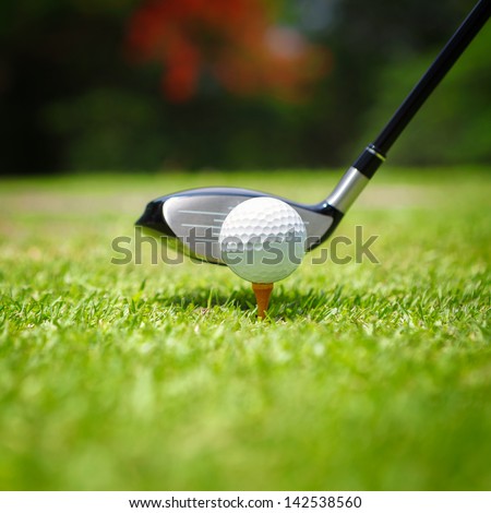 Golf ball on tee in front of driver
