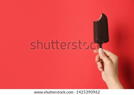 Woman holding delicious ice cream with chocolate against color background, space for text