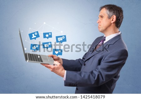 Man holding laptop with different types of social media symbols and icons