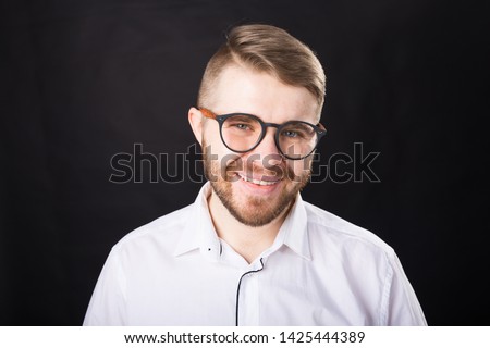 Portrait of smiling bearded handsome man looking at camera isolated over black background