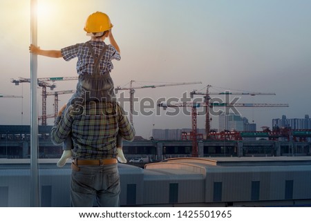 Asian boy on father's shoulders with background of new high buildings and silhouette construction cranes of evening sunset, father and son concept Royalty-Free Stock Photo #1425501965
