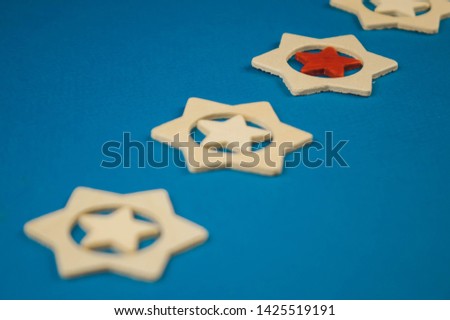 five wooden stars and one of them is red on a blue background