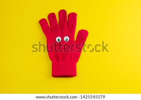 top view red  glove  with googly eyes isolated  on a yellow background