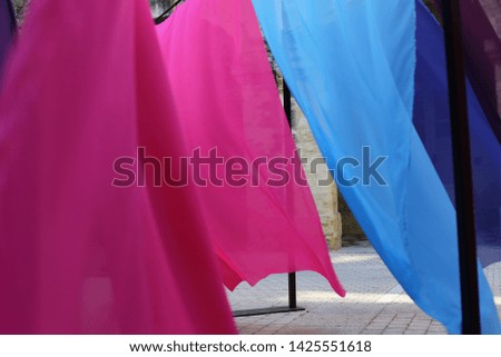 Close up outdoor view of moving colorful tissues. Abstract image with silky blue and pink fabrics. Background made of flowing movements created by the wind. Symbol of beauty, motion and elegance.