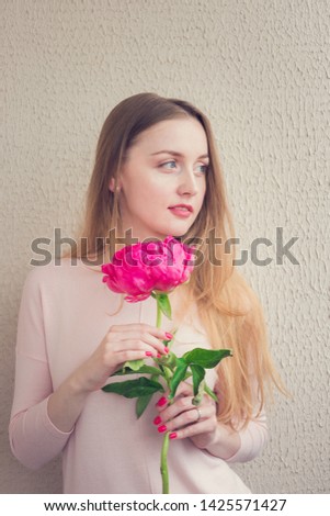 Attractive woman with peony in her hands, young woman looking away, portrait, vertical