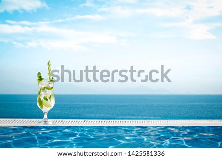 Summer drink and swimming pool background with landscape of ocean. 
