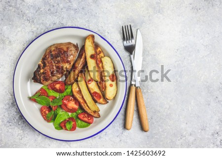Grilled steaks, French fries and vegetables on light gray background. Top vew