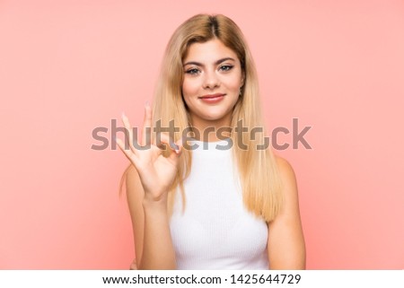 Teenager girl over isolated pink background showing an ok sign with fingers
