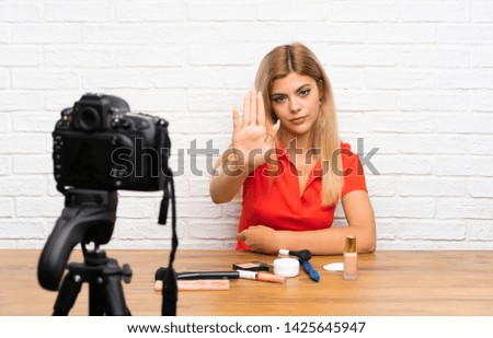 Teenager blogger girl recording a video tutorial making stop gesture with her hand
