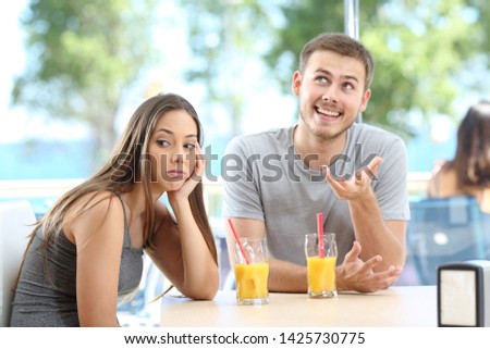 Bored girl listening a bad conversation from a friend or partner in a coffee shop or hotel on the beach Royalty-Free Stock Photo #1425730775