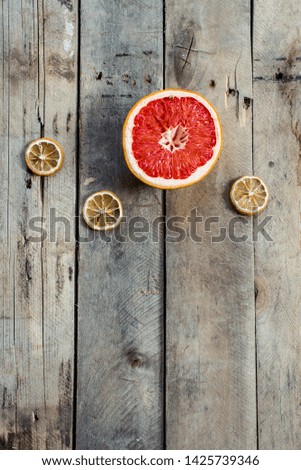 One half of red ripe grapefruit and three slices of dry decorative tangerines on an old wooden retro background in vintage style. Falling fruit. trendy flatlay. stylish food photography. Copy space