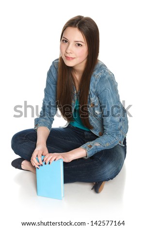 Young smiling relaxed female student sitting on floor with a book, isolated on white