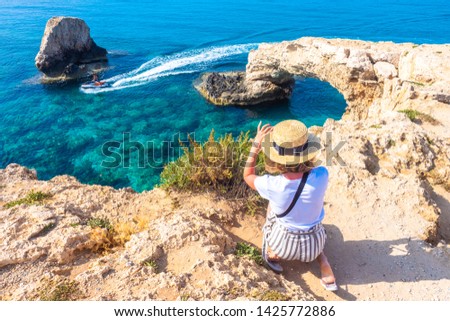 Cyprus. Tourists at Love bridge. The girl takes pictures of the bridge of love from above. The cliffs in the ocean water. The Cape Greco. Ayia Napa. The  riding a water scooter in Mediterranean sea.