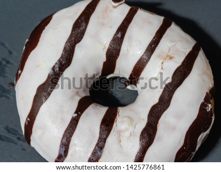 close up of vanilla donuts on table. The donuts have white glaze with brown stripes