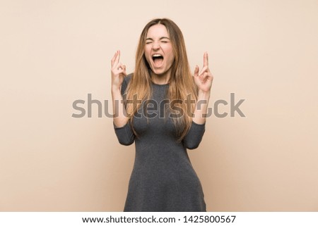 Young woman over isolated background with fingers crossing