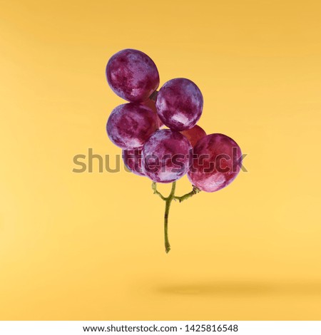 Fresh ripe grape falling in the air isolated on yellow background