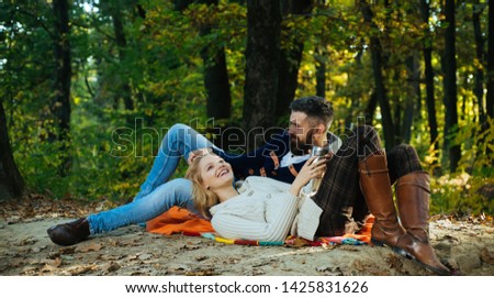 Autumn couple in love hug. Young lovers enjoying each other at a picnic. Woman lying down on the man's leg and having a romantic moment together. Beautiful autumn outside. Couple in loving