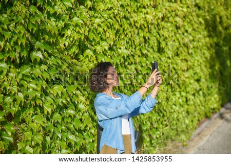 
Woman with a smartphone near vegetation.