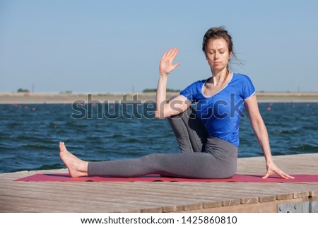 Woman making yoga exercise at a lake. Portrait