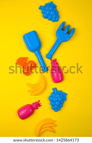multicolored plastic toys fruits on a yellow  background, close up