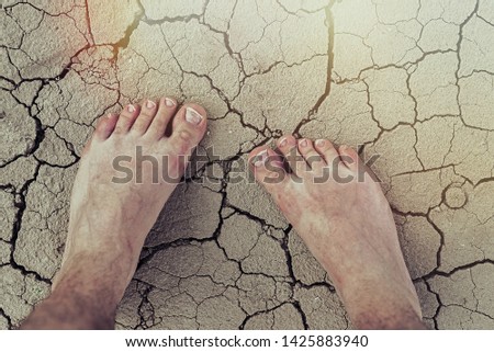 Dry skin of the feet, foot care, pedicure concept. Male foot on the dry cracked earth.
